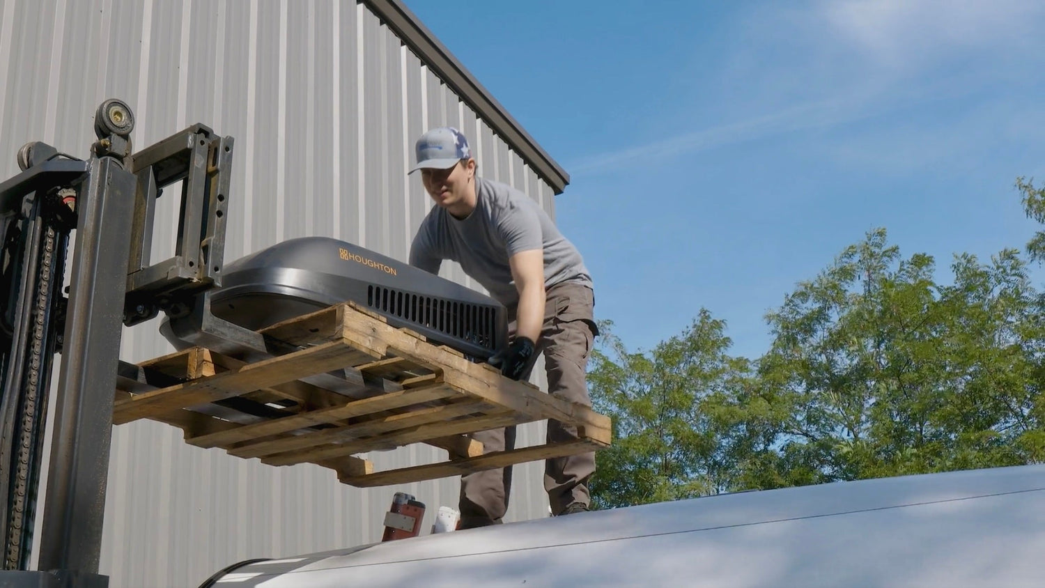 Lifting new RecPro AC unit onto RV roof using a forklift