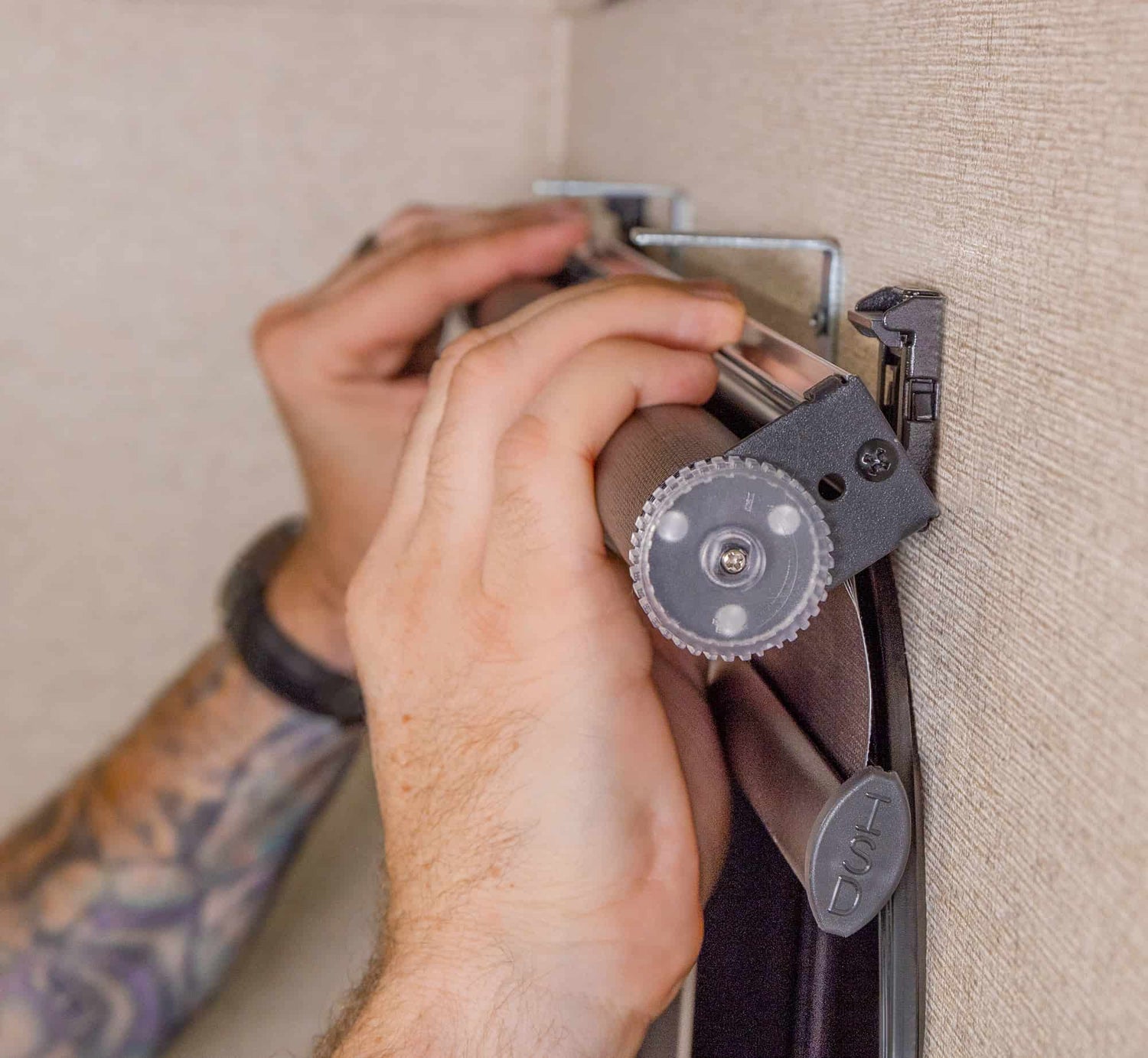 Close up view of a person's hands snapping a roller shade into RV mounting brackets.